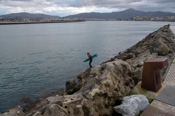 Fototapeta na wymiar Mujer surfista entrando al agua para surfear en Hondarribia
