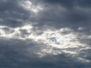 Natural sky background. The sky is covered with dark gray-blue cumulus clouds, in the center of the frame a light area that turns from white to blue.