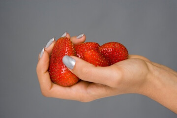 Obraz premium mão com unhas pintadas a segurar morangos