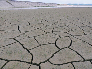 Fototapeta na wymiar Dried up hydroelectric dam with deeply cracked soil