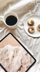 A cup of coffee on a bed with cookies and a tablet. Morning 