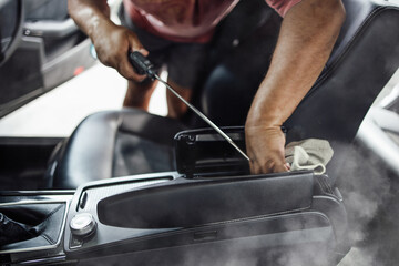 Car wash service worker wet cleaning vehicle interior and seats. Old car restoration work.