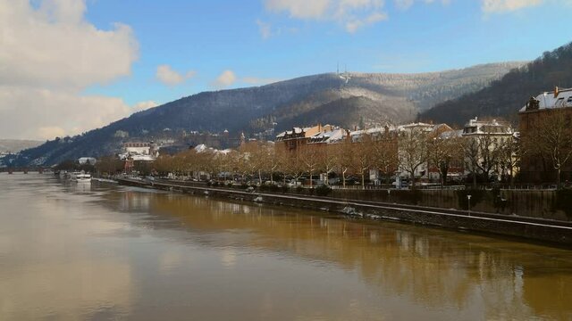 Heidelberg, Germany - February 2021: View on Odenwald forest hill with historical castle and neckar river. View from Theodor Heuss bridge on sunny winter day with snow