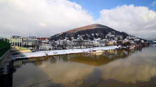 Heidelberg, Germany - February 2021: View on Odenwald forest hill called Heiligenberg with historical mansions covered in snow and neckar river. View from Theodor Heuss bridge on sunny winter day.