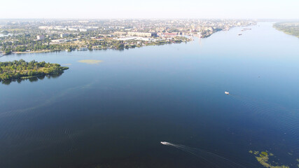 Drone fly over waving river of blue color surrounded by local village with various buildings and Wetland and marsh habitat with a reedbed of Common Reed aerial view.