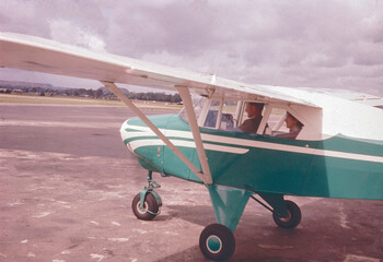 A turquoise blue 2-passenger seater from the 1960s, photographed from a left-back angle. The image captures the front, wing, and cockpit of the plane, suggesting it's ready for take off.