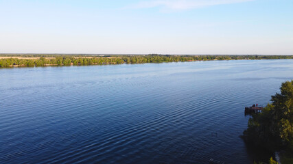 Drone fly over waving river of blue color surrounded by local village with various buildings and Wetland and marsh habitat with a reedbed of Common Reed aerial view.