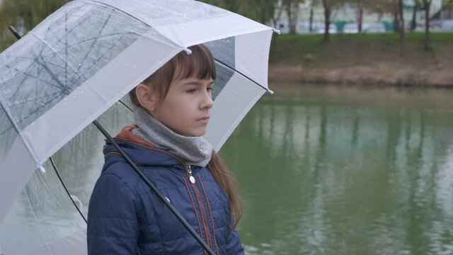Walk in park under umbrella. A view of sad teen staying alone with an umbrella in the park.
