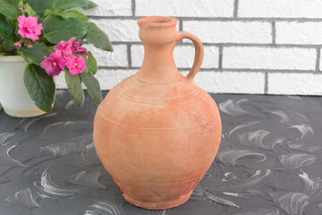 Old brown earthenware jug with chips. Vintage vessel in home, hand-made