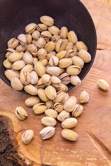 Nuts, of Pistacia in the shell poured from the dark Cup on wooden background