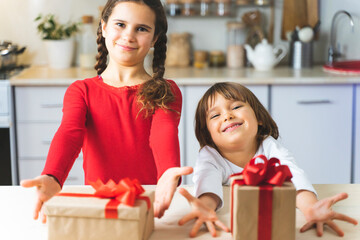 The children received gifts for the holiday. Happy kids open gift boxes for Valentine's Day. Brother and sister have fun and rejoice in surprise