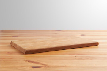 new rectangular wooden cutting board, in top of wooden table with a minimalistic limbo background