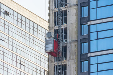 Construction elevator outside the facade of a multi-storey building under construction.