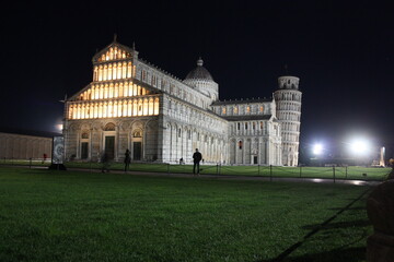 Fototapeta na wymiar Piazza Miracoli in Pisa seen at night between monuments such as the tower and the solitude of the global pandemic in the dark