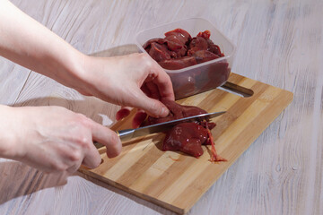Cut the chicken liver on a wooden board with a knife to prepare the finished dish