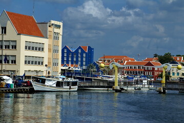 Ships in the harbor in Sint Anna Bay, in front of colorful buildings along the waterfront in...