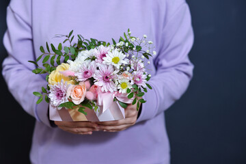 a girl in a soft purple sweatshirt holds a bouquet in her hands.