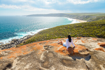 Woman enjoying the scenery while sitting on the edge of the cliff at Remarkable Rocks, Kangaroo Island, South Australia