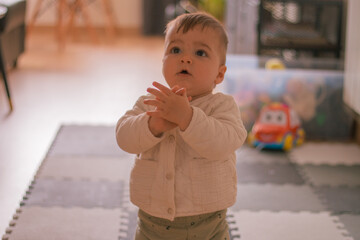 Little caucasian baby boy clapping his hands while sitting on the floor. 