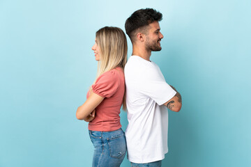 Young caucasian couple isolated on blue background keeping arms crossed