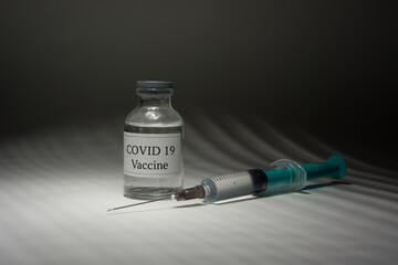 Covid 19 vaccine bottle and syringe on a black background.