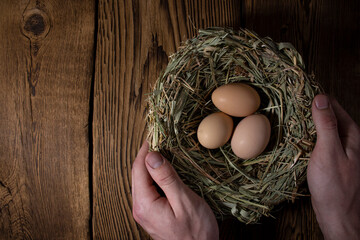 easter basket with eggs in hands on vintage wooden background with copy space