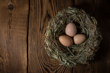 easter basket with eggs in hands on vintage wooden background with copy space
