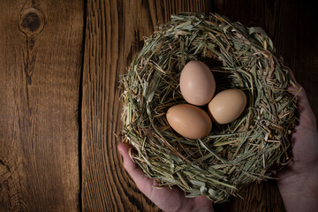 easter basket with eggs in hands on vintage wooden background