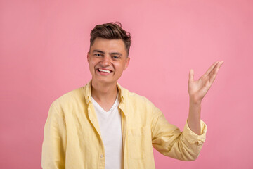 Happy smiling young man presenting and showing your text or product isolated on pink background