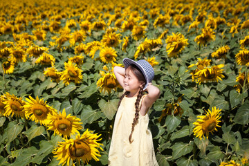 Funny small girl in a field of sunflowers