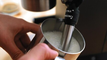 Barista steaming milk in a pitcher. Wife whips milk with steam in a pitcher at home