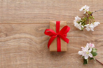 Fototapeta premium Gift box with cherry flowers on the wooden background.