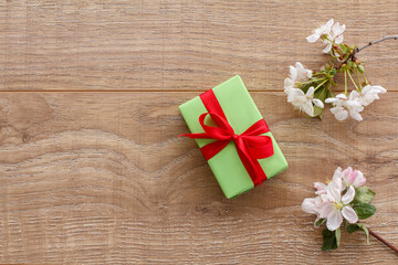 Fototapeta premium Gift box with cherry flowers on the wooden background.