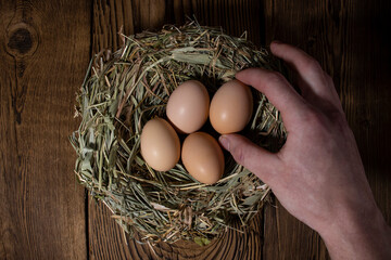 easter basket with eggs in hands on vintage wooden background