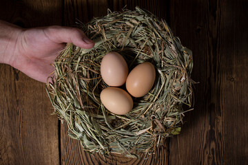 easter basket with eggs in hands on vintage wooden background