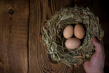 easter basket with eggs in hands on vintage wooden background