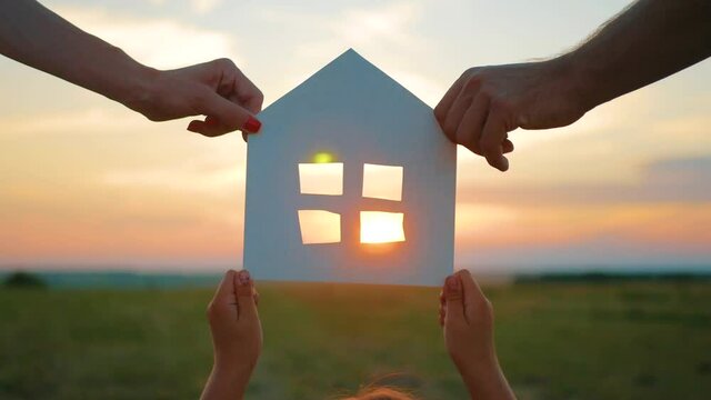 Silhouette hands family with paper house at sky sunset background.