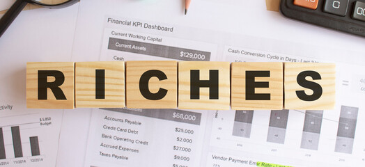 Wooden cubes with letters on the table in the office. Text RICHES.