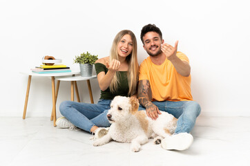 Young caucasian couple with dog staying at home inviting to come with hand