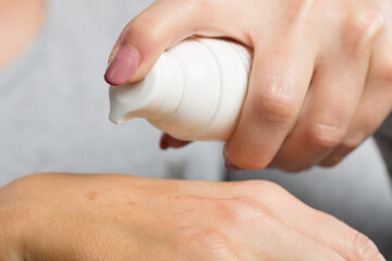 Close up of applying skin lotion on female hand to avoid dry hands