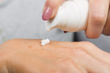 Close up of applying skin lotion on female hand to avoid dry hands