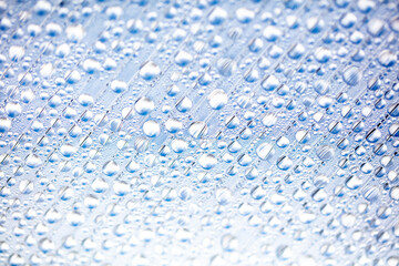 Water drops on blue glass as an abstract background.