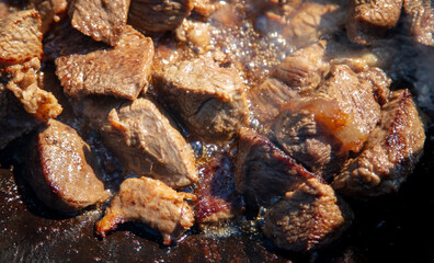 The meat is fried in a cauldron.