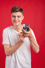 Fototapeta premium Say cheese! Young man take photo with retro dslr camera looking at camera over gray abackground. Portrait of positive man in hat with retro camera standing isolated