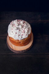 Easter cakes on wooden stand decorated with marshmallows, dark background, top view