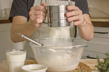 A male baker kneads bread dough in his kitchen. Home baker