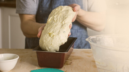 A man without a face in an apron holds raw bread dough in his hands, a home baker. Authentic home cooking hobby