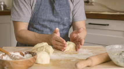 A man rolls dough on the table in the kitchen. Homemade bread baking