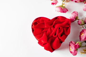 Red heart shaped gift box and flowers on white background
