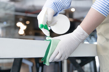 Close up Staff hand Restaurant workers are cleaning table and spraying disinfectants during the virus outbreak, Using cleaning solutions or using alcohol to kill germs in the restaurant.